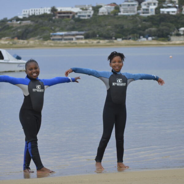 two young kids standing in wetsuits at Plettenberg Bay Lagoon