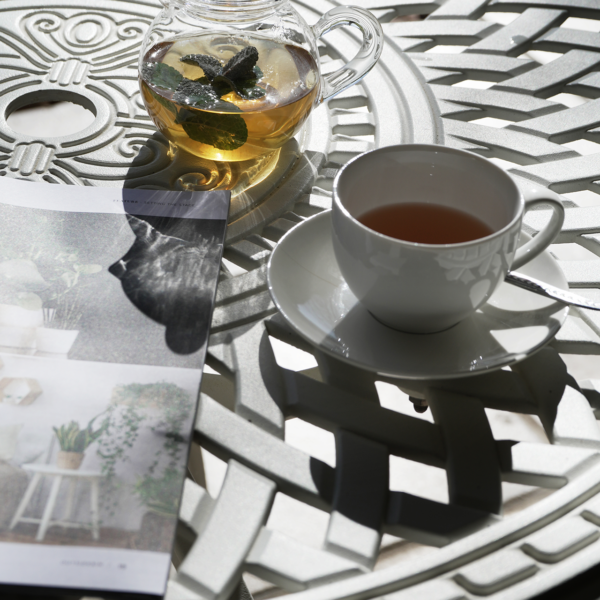 herbal teapot, cup and saucer on wrought iron table